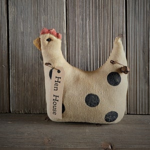 May include: A beige fabric chicken with black polka dots and a red comb. The chicken has a tag that says "Hen House".