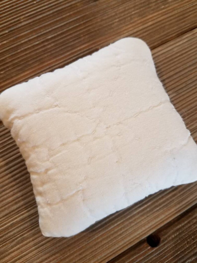 May include: A white quilted pillow with a star-shaped design. The pillow is made of a soft, textured fabric.