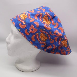 May include: Blue surgical scrub cap with a repeating pattern of orange intestines and the words "Colorectal Surgery" and "Come for the Guts, Stay for the Butts". The cap is designed to be worn in a medical setting.