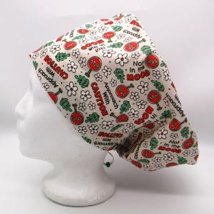 Può includere: Un cappuccio scrub color crema con un motivo ripetuto di segnali di stop rossi, fiori bianchi e foglie verdi. Il cappuccio presenta anche le frasi "Approach with Caution" e "Not in the Mood."