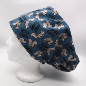 May include: A blue scrub cap with a repeating pattern of cartoon squirrels and the text "SQUIRREL PATROL" in white. The squirrels are in shades of brown and tan.