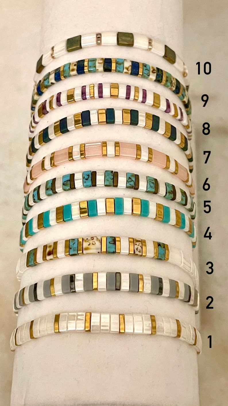 May include: Ten stacked bracelets with different colored beads and gold accents. The bracelets are numbered 1 through 10.