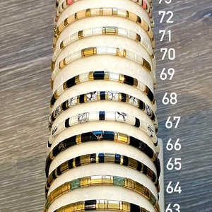 May include: A stack of 16 gold and black bracelets with different colored beads, numbered 60 to 76.