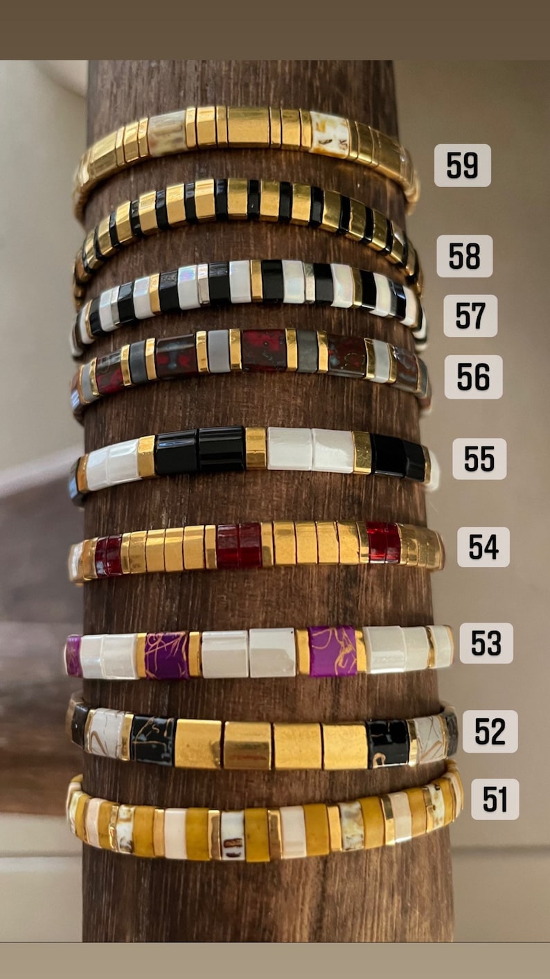 May include: A close-up of ten stacked bracelets with gold and colorful beads. The bracelets are numbered 51 through 59.