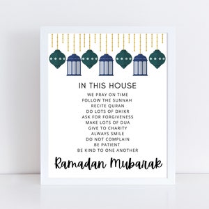 May include: A framed print with a white border features the text "IN THIS HOUSE" above a list of values. The top of the print has a decorative design of teal lanterns and gold accents. The words "Ramadan Mubarak" are written in cursive at the bottom.
