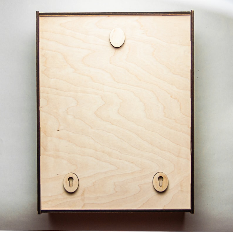 May include: A light wood frame with a smooth surface and three keyhole-shaped cutouts. The frame is ready to be hung on a wall.