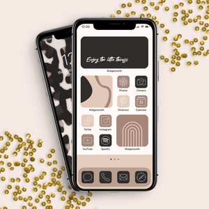 May include: A smartphone with a black background and a brown and white abstract design. The phone's home screen is customized with a light brown background and icons for apps like TikTok, Instagram, YouTube, Spotify, and Pinterest. The text "Enjoy the little things." is displayed at the top of the screen.
