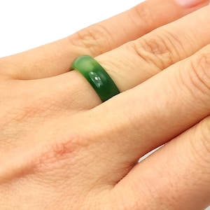 May include: A simple green ring made of jade, worn on a finger.
