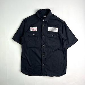 May include: Black short-sleeved button-up shirt with two chest pockets and patches. One patch reads "Practice DAUNTLESS" and the other says "LIFE IS ONLY ONCE, SO ENJOY WITH EVERYONE, THE LIFE IS BEAUTIFUL."
