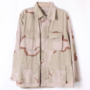 May include: A desert camouflage jacket in shades of tan and brown, featuring four front pockets and a collared neckline. The jacket has a button-up front and long sleeves. The pattern is a desert camouflage design.