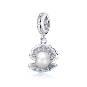 May include: A silver charm featuring a pearl inside a clam shell with clear cubic zirconia stones. The charm has a silver loop for attaching to a bracelet or necklace.