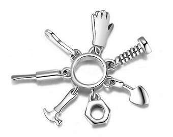May include: Silver charm bracelet with a variety of tools, including a hammer, screwdriver, wrench, and a nail. The charm is attached to a silver ring.