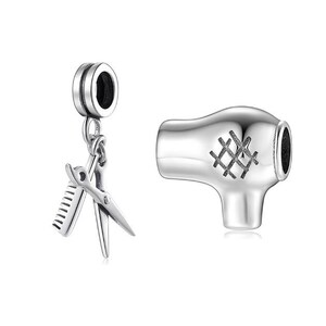 May include: Silver charm set for a bracelet, featuring a hair dryer and a pair of scissors and a comb.