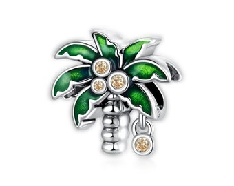 Op de afbeelding: Een zilveren bedel in de vorm van een palmboom met groene emaillebladeren en heldere kristallen accenten. De bedel heeft een kleine hangende bedel met een helder kristal.