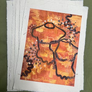 May include: A stack of handmade paper with a colorful abstract painting. The artwork features orange, yellow, and brown hues with black line art and decorative elements. The painting is signed in the bottom right corner.