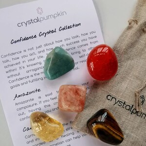 May include: A set of six tumbled crystals for confidence, including amazonite, carnelian, clear quartz, red jasper, rose quartz, and tiger's eye. The crystals are arranged on a white background with text about confidence.