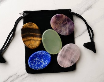 May include: A black velvet pouch with six smooth, polished gemstone palm stones. The stones are in various colors, including green, purple, pink, brown, and blue.