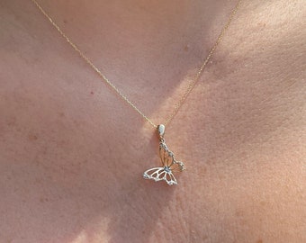 May include: A delicate gold necklace featuring a butterfly pendant. The butterfly design is adorned with small, sparkling accents. The necklace is displayed against a dark background.