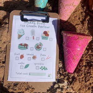 Puede incluir: Un formulario de pedido de helado imprimible con una lista de verificación de ingredientes, que incluye fruta, salsa, copos, obleas y chispas. El formulario está en un portapapeles con un cono de helado rosa y azul a cada lado.