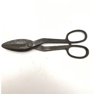 May include: A vintage metal pair of tin snips with a curved blade and two handles. The snips are rusty and have a worn finish.