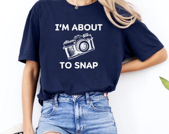 May include: A navy blue t-shirt with white text that reads "I'm about to snap" and a white illustration of a vintage camera.