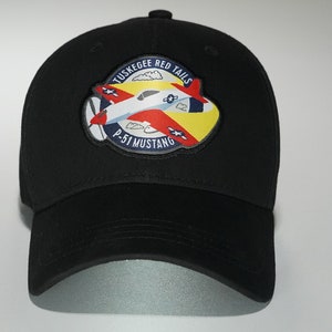 May include: Black baseball cap with a red, white, and blue patch featuring a plane and the text "Tuskegee Red Tails P-51 Mustang".