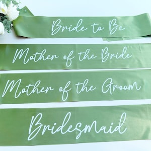 May include: Four green satin sashes with white text. The sashes read "Bride to Be", "Mother of the Bride", "Mother of the Groom", and "Bridesmaid".