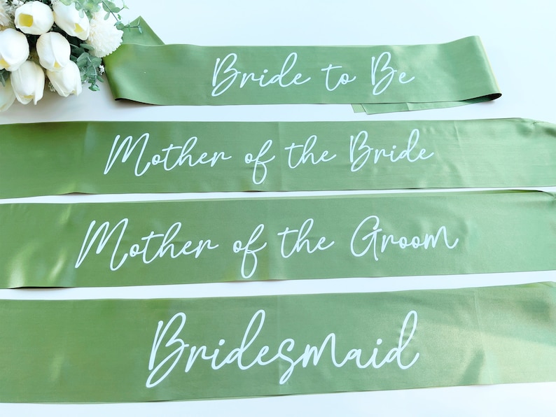 May include: Four green satin sashes with white text. The sashes read "Bride to Be", "Mother of the Bride", "Mother of the Groom", and "Bridesmaid".