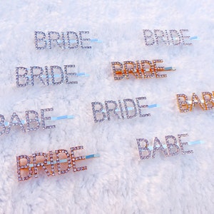 May include: A set of eight rhinestone hair clips with the words "Bride" and "Babe" in silver and gold.