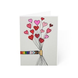 May include: A folded greeting card featuring a hand-drawn illustration of a bouquet of hearts in shades of red and pink. The bouquet is held by a hand with a rainbow and progress pride flag design. The card is on a white background.