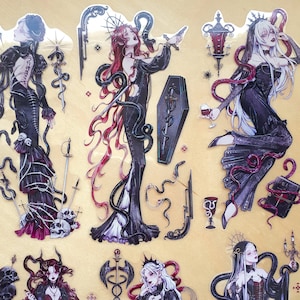 Puede incluir: Un conjunto de seis pegatinas de estilo gótico con mujeres en vestidos negros con detalles rojos. Las pegatinas están sobre un fondo beige y presentan detalles intrincados como serpientes, calaveras y flores.