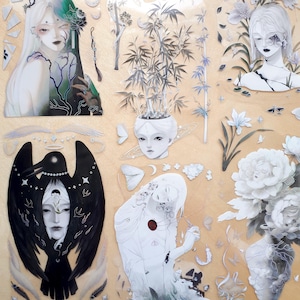 May include: A collection of artistic stickers featuring ethereal figures, flowers, and celestial elements in shades of white, black, and green. The stickers include illustrations of faces, plants, and decorative accents, all set against a light tan background.