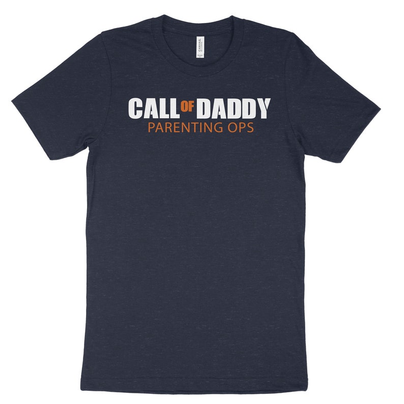 May include: A navy blue t-shirt with the text "CALL OF DADDY PARENTING OPS" in white letters. The word "OF" is in orange.