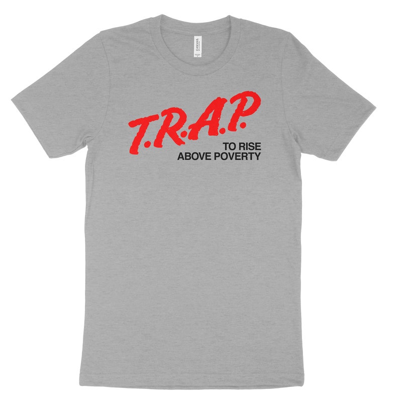 Puede incluir: Camiseta gris con texto rojo que dice "T.R.A.P. To Rise Above Poverty".