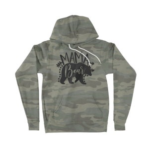May include: A green camouflage hoodie with a black silhouette of a bear and the text "Mama Bear" with arrows on either side.