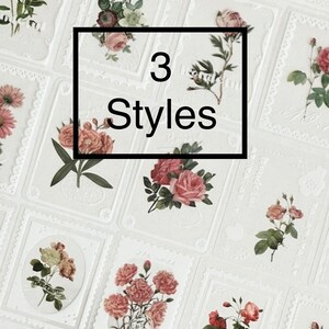 May include: A sheet of white paper with 3 different styles of floral stickers. The stickers are in the shape of a rectangle with a decorative border. The flowers are pink, white, and yellow.