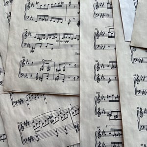 May include: A collection of overlapping off-white sheet music pages featuring black printed musical notation, treble and bass clefs, and various tempo markings such as Sempre pp, Poco cal, and cresc, with numbered measures throughout the composition.