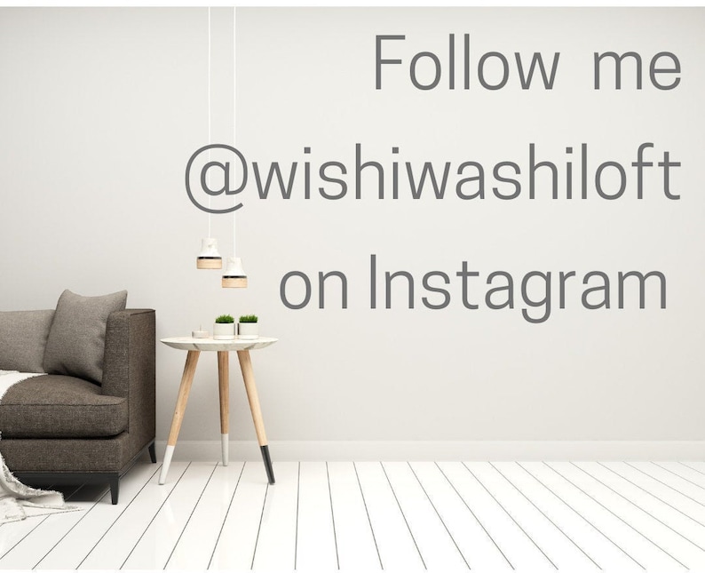 May include: A gray couch with a throw blanket sits in a room with white walls and white wood floors. Two hanging lights are visible above a small wooden table with two potted plants. The text "Follow me @wishiwashiloft on Instagram" is written on the wall.