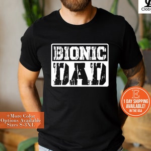 May include: Black t-shirt with white text that reads "BIONIC DAD" in a distressed font.