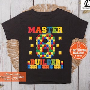 May include: Black t-shirt with a colorful design that says "MASTER 8 BUILDER" with a number 8 made of colorful blocks.