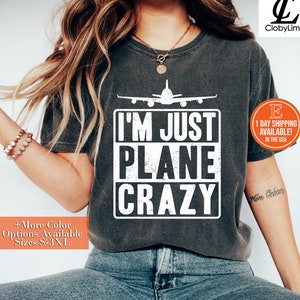 May include: A dark gray t-shirt with a white airplane graphic and the text "I'm Just Plane Crazy".