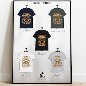 May include: A framed display of t-shirts in navy, dark heather, black, white, and grey. Each shirt features the text "SOME GRANDPAS TAKE NAPS, REAL GRANDPAS PLAY GUITAR THEN TAKE A NAP" with crossed guitars. The brand logo is at the bottom.