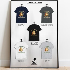 May include: A framed display of t-shirts in various colors: navy, dark heather, black, white, and grey. Each shirt features a cartoon frog with a sword and the text "I AM A CONDUIT FOR NONSENSE". The display includes the text "COLOR OPTIONS".