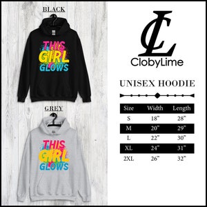 Puede incluir: Sudadera con capucha unisex con el texto "This Girl Glows" en letras de colores. La sudadera est&aacute; disponible en negro y gris. Tabla de tallas con medidas de ancho y largo en pulgadas.
