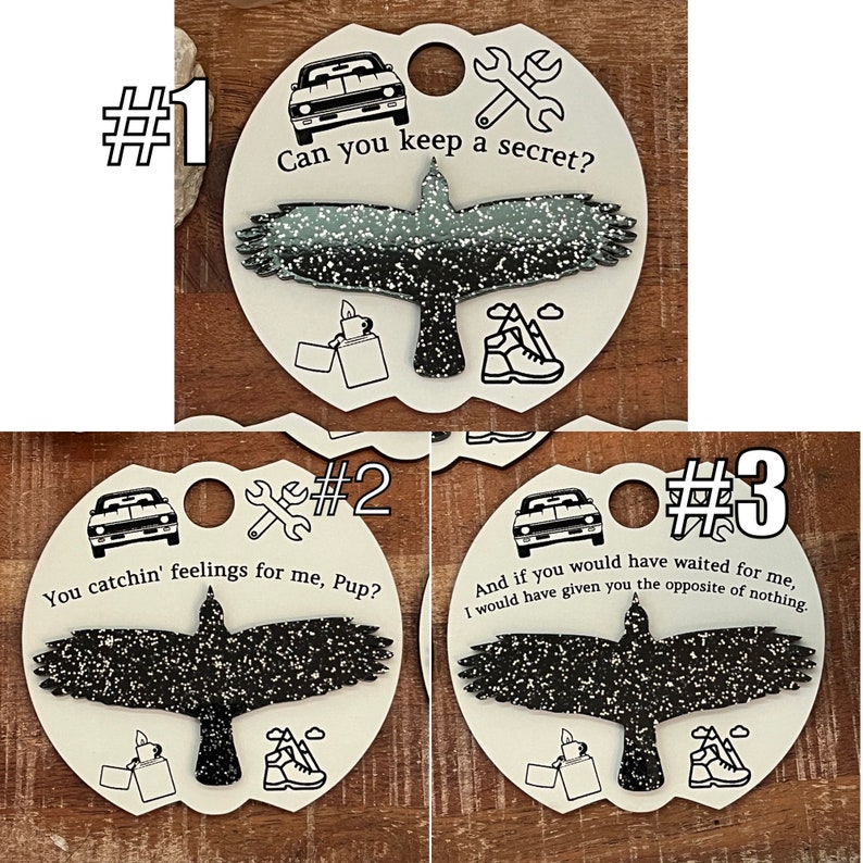 May include: Three round white keychains with black and white images of a bird, a car, and a wrench. Each keychain has a different saying: "Can you keep a secret?", "You catchin' feelings for me, Pup?", and "And if you would have waited for me, I would have given you the opposite of nothing."