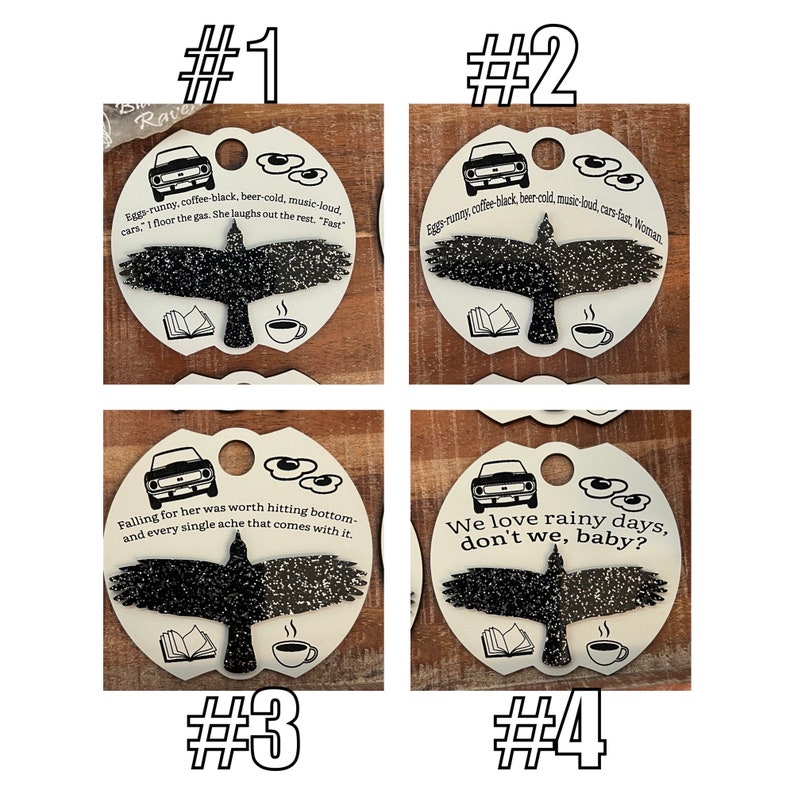 May include: Four white ceramic ornaments with black and white illustrations of a car, a raven, a book, and a coffee cup. Each ornament has a different quote printed on it. The quotes are: "Eggs-runny, coffee-black, beer-cold, music-loud. cars, "I floor the gas, she laughs out the rest. "Fast" ", "Eggs-runny, coffee-black, beer-cold, music-loud, cars-fast, Woman", "Falling for her was worth hitting bottom- and every single ache that comes with it.", and "We love rainy days, don't we, baby?"