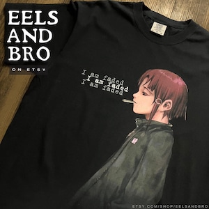 May include: A black short-sleeve t-shirt featuring a graphic of a person with short reddish-brown hair wearing a dark jacket and holding a cigarette. The text "I am faded" is printed three times in white above the figure. The shirt has a crew neck.