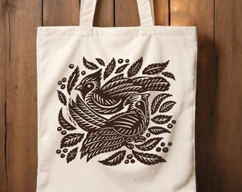 Ilustración estilo grabado en madera de pájaros en un bolso de algodón. Este bolso bandolera ecológico es práctico y elegante, perfecto para el uso diario.
