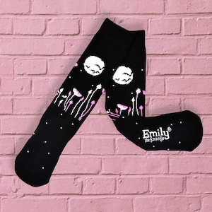 May include: Black knee-high socks with a white moon and bats design, pink flowers, and white polka dots. The socks have the text "Emily the Strange" on the heel.