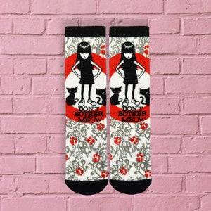 May include: A pair of white crew socks with a black and red design. The socks feature a cartoon girl with black hair and a red circle with the text "Don't Bother Meow". The socks have a white background with a gray and red floral pattern.